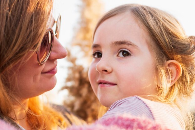 Mother embracing cute daughter close up