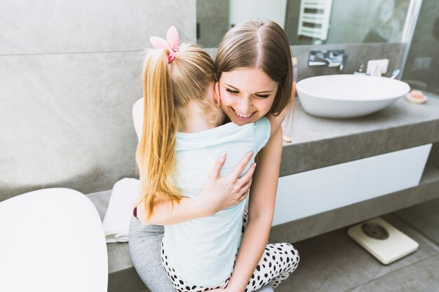 Mother embracing daughter in bathroom