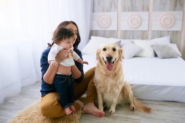 The mother embracing her daughter and sitting near dog