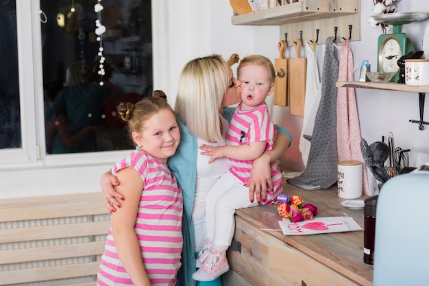 Free photo mother embracing and kissing daughters