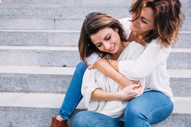 Madre che abbraccia la giovane donna dalla schiena