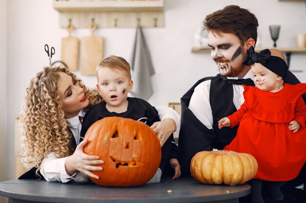 Мать, отец и дети в костюмах и макияже. Семья готовится к празднованию Хэллоуина.