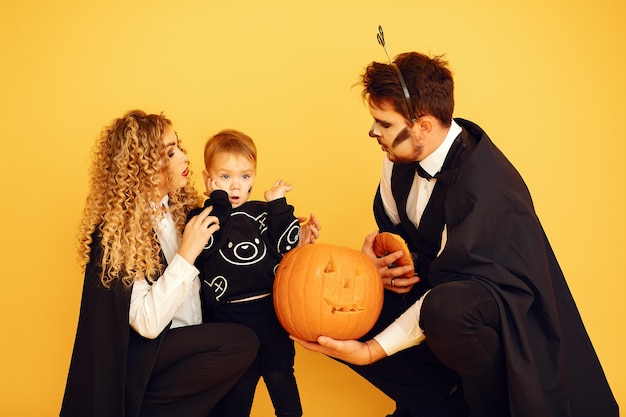 Madre, padre e figli in costume e trucco. persone in piedi su uno sfondo giallo.