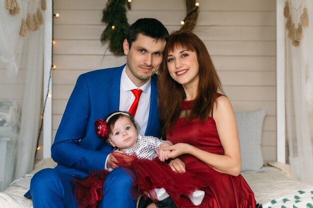 The mother, father and daughter sitting on the bed