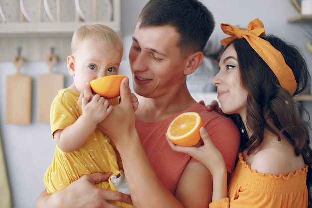 Мать и отец кормят дочь апельсином