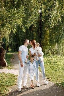 Мать, отец, старший сын и маленькая дочка ребенка гуляют в парке. семья в бело-голубой одежде