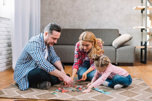 Mother and father playing puzzle pieces with their daughter