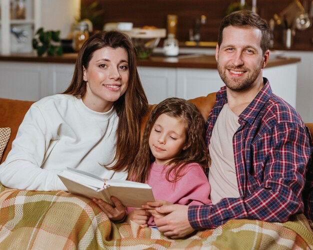 Mother and father reading book at home with daughter