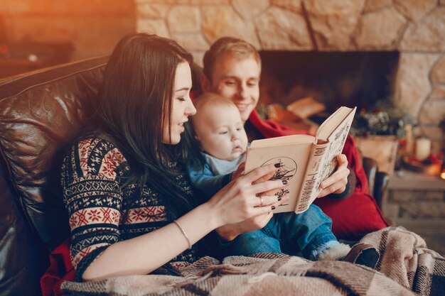 Mother and father reading a book with baby in the middle