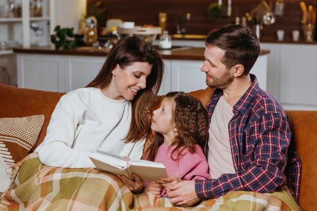 Mother and father reading book with daughter at home