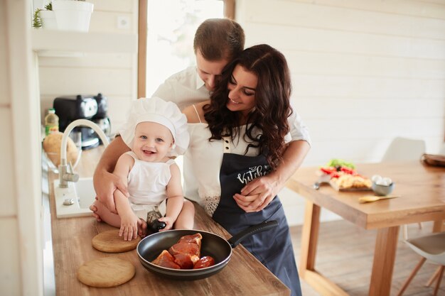 The mother, father and son cooking a meat