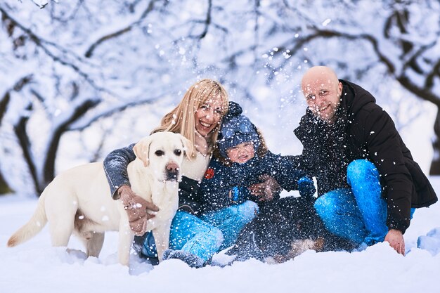 雪の上に座っている母親、父親、息子、犬