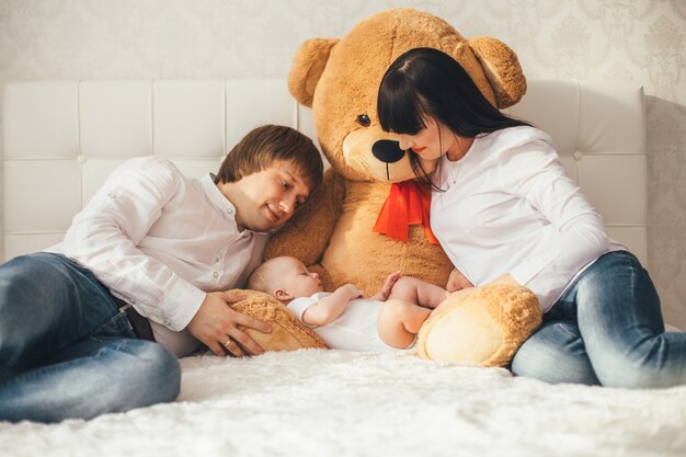 Мать, отец и сын лежат возле медведя на кровати