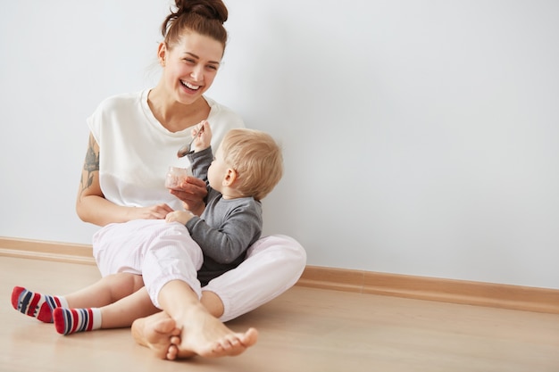 スプーンで彼女の男の子に餌をやる母