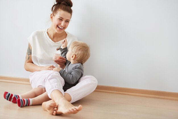 スプーンで彼女の男の子に餌をやる母