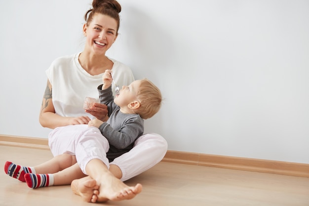 スプーンで彼女の男の子に餌をやる母