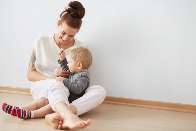 スプーンで彼女の男の子に餌をやる母