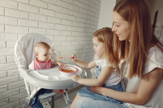 Free photo mother feeding her little baby in a kitchen