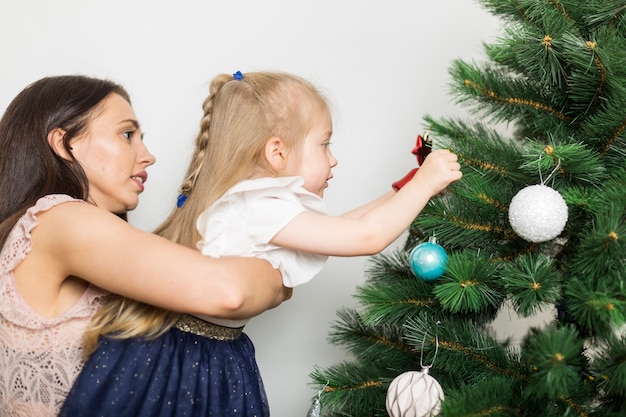 母と女の子、クリスマスツリーを飾る