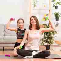 Free photo mother and girl at home working out