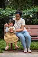 Free photo mother and girl sitting on bench full shot