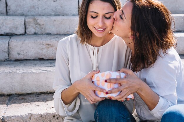 mother giving present and kissing woman