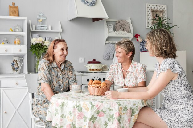 Foto gratuita madre; grand figlia e nonna seduti in cucina e sorridente