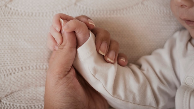 赤ちゃんの小さな腕を持っている母の手