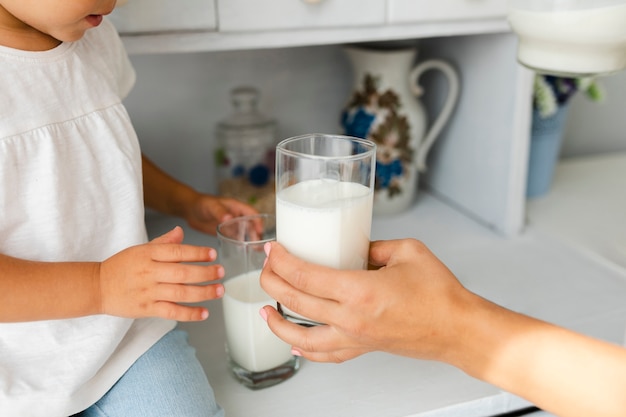 Матери руку, предлагая стакан молока