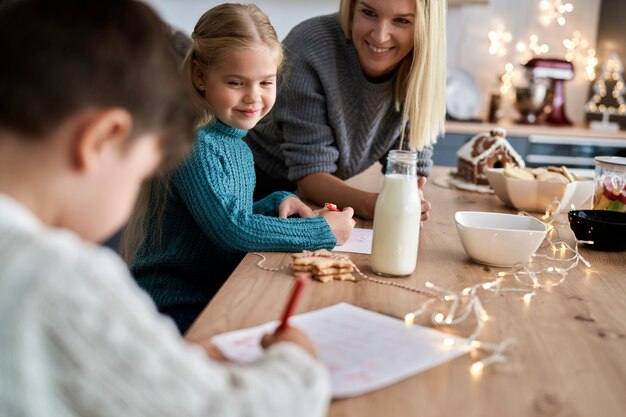 子供たちがサンタクロースに手紙を書くのを手伝う母親