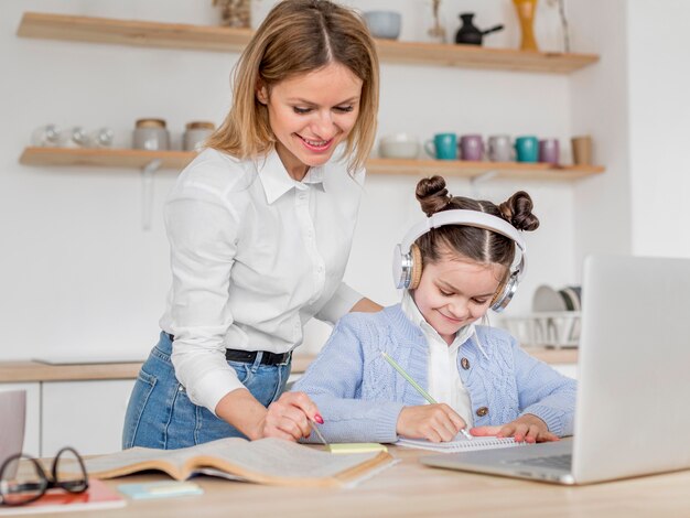 Mother helping her daughter at an online class