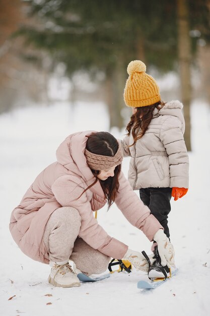 Mother helping her daughter to put her skies