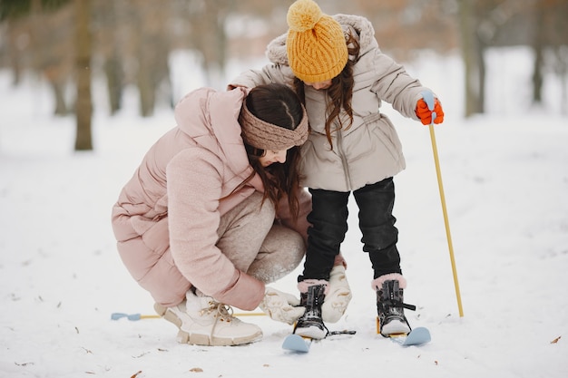 Mother helping her daughter to put her skies