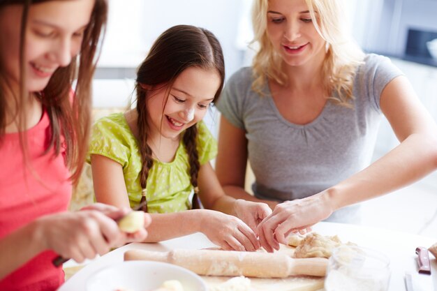 Mother helping her daughter with pizza dough