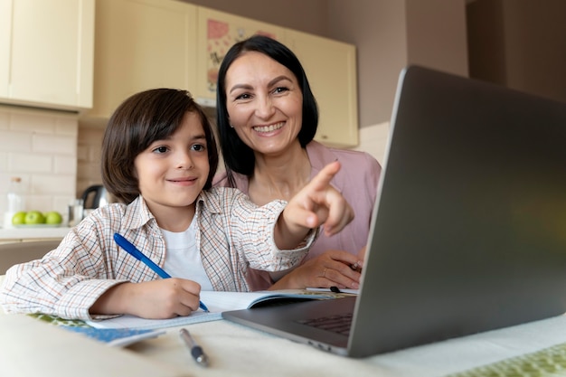 Foto gratuita madre che aiuta suo figlio in una lezione online