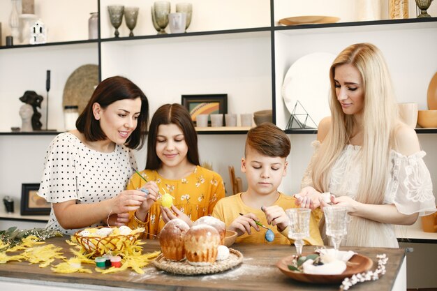 Mother helps her son to draw. Children at table. Mom is blonde.