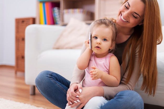 Mother and her baby using mobile phone at home