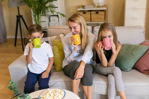 Mother and her children drinking from cups front view