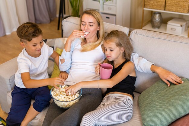 Мать и ее дети едят попкорн высокий вид
