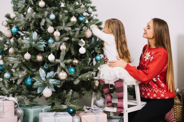 母と彼女の娘はクリスマスツリーを飾る