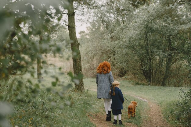 엄마와 강아지와 함께 연주 그녀의 딸입니다. 가을 공원에서 가족. 애완 동물, 가축 및 생활 양식 개념. 가을 시간.