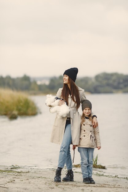 Mother and her daughter playing with dog. Pet, domestic animal and lifestyle concept