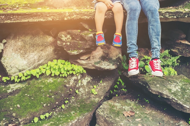 Mother and her little son feets sitting at the cliffside.