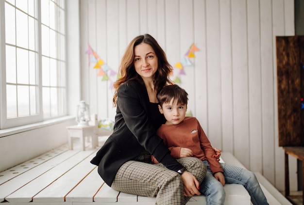 Mother and her son are posing in the studio and wearing casual clothes