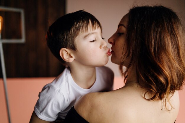 Mother and her son are posing in the studio and wearing casual clothes