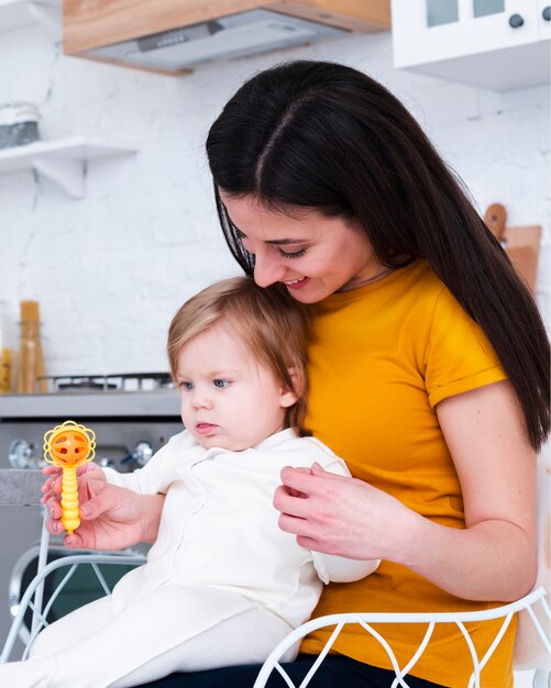 Mother holding baby playing with toy