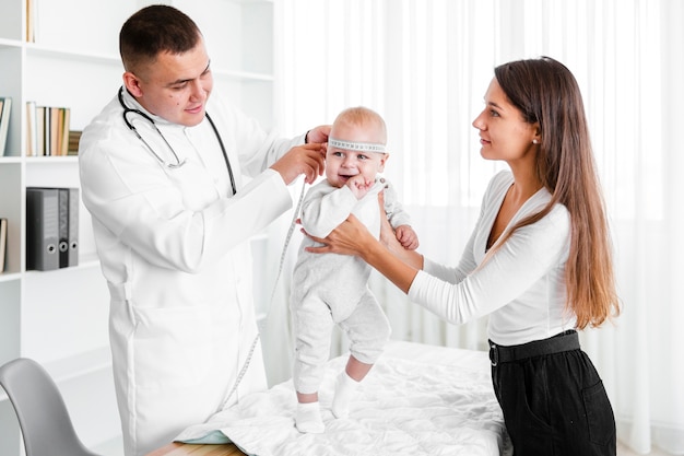 Mother holding baby while doctor looking at it