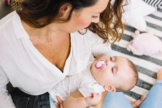 Mother holding child sleeping with dummy