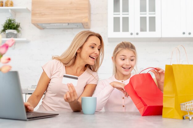 Foto gratuita generi la tenuta della carta di credito e la figlia che guardano in sacchi di carta