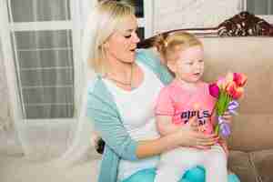 Free photo mother holding daughter with tulips